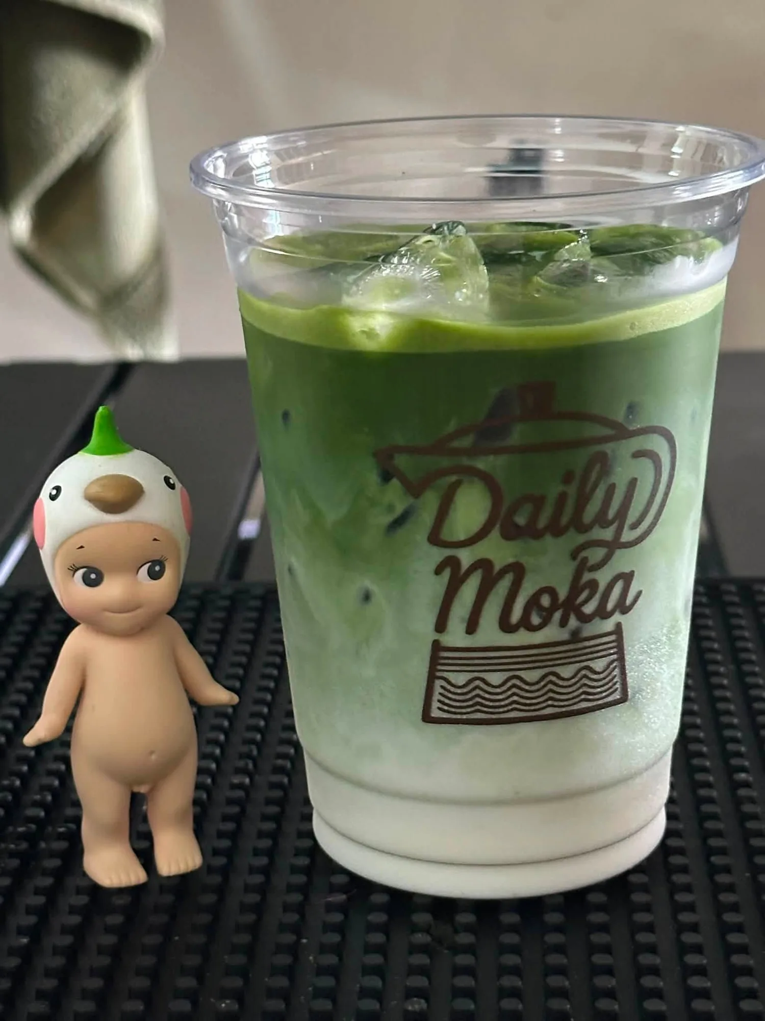 Iced matcha in a clear cup with the Daily Moka logo